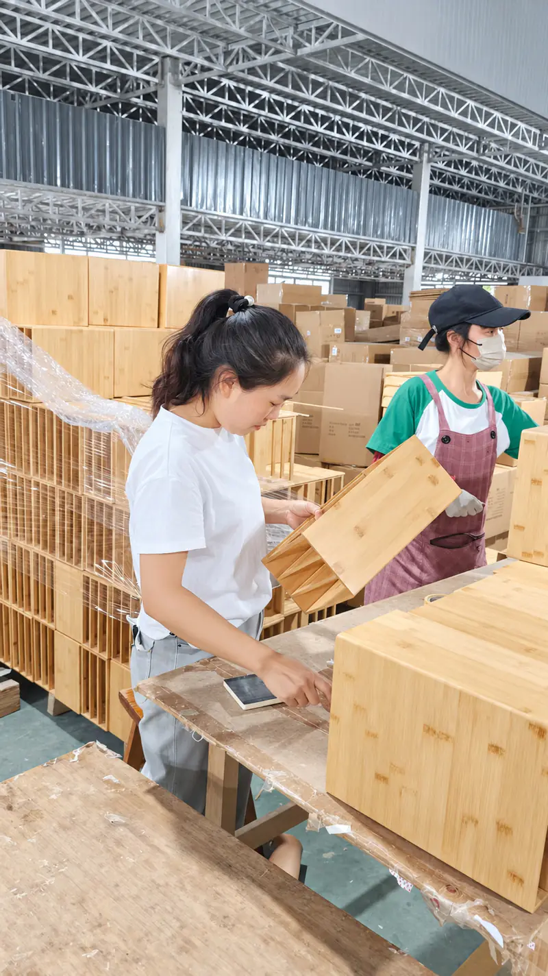 Workshop staff handling bamboo boxes and panels at an inspection table