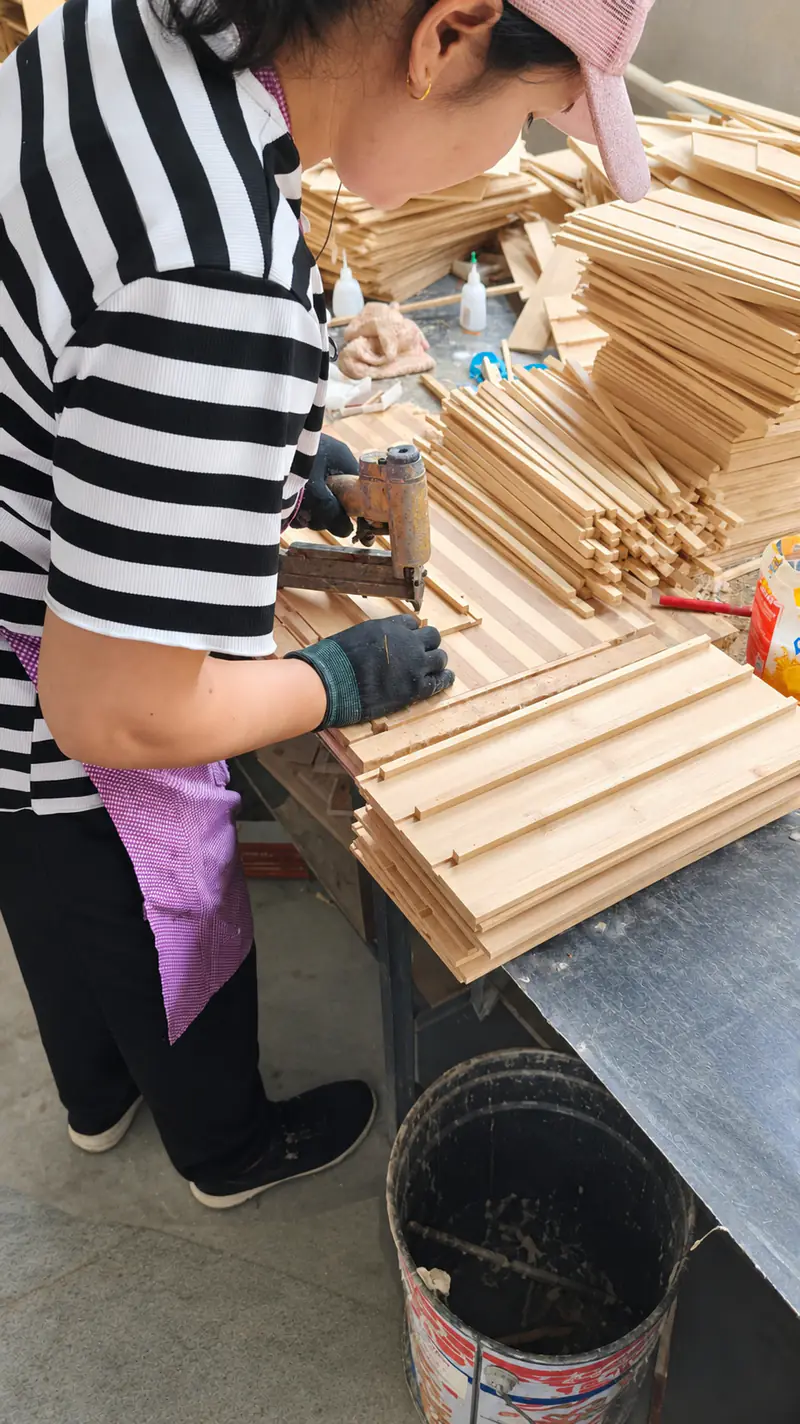 A worker positioning bamboo box panels on a workbench